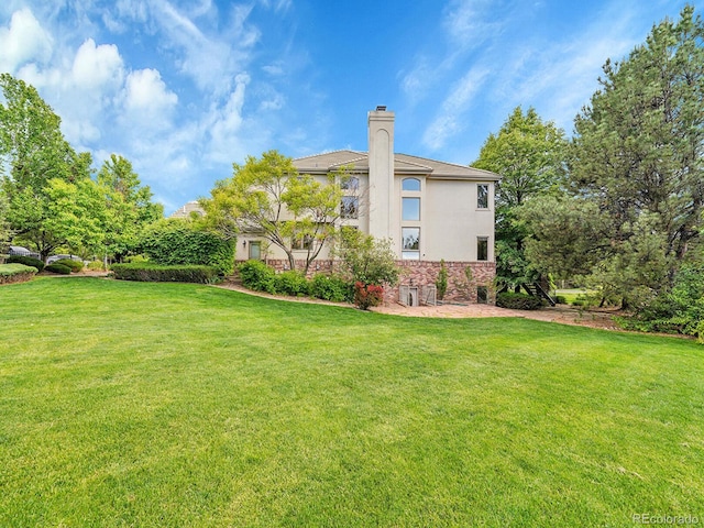 291 Fairchild Dr, Highlands Ranch, CO 80126 - back of house featuring stucco siding, a lawn, a chimney, and stone siding
