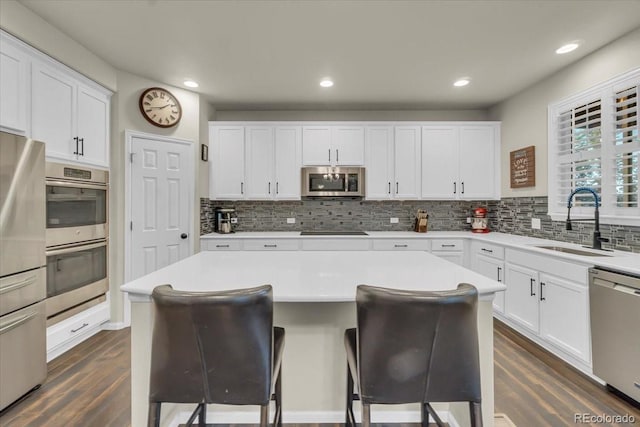 3762 White Rose Loop, Castle Rock, CO 80108 - kitchen featuring appliances with stainless steel finishes, dark wood-style flooring, backsplash, a breakfast bar, and white cabinets