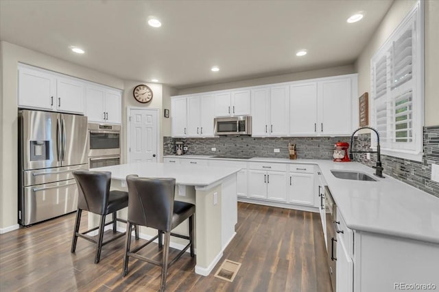 3762 White Rose Loop, Castle Rock, CO 80108 - kitchen featuring appliances with stainless steel finishes, dark wood-type flooring, a kitchen breakfast bar, decorative backsplash, and recessed lighting