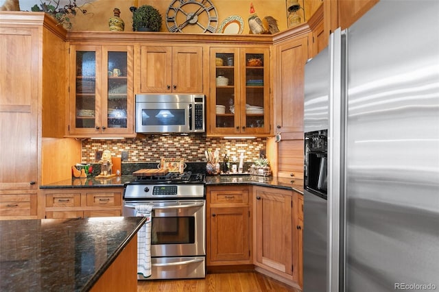 1045 Golden Hills Rd, Colorado Springs, CO 80919 - kitchen featuring backsplash, appliances with stainless steel finishes, glass insert cabinets, and dark stone countertops