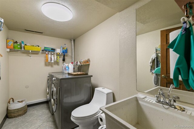 1045 Golden Hills Rd, Colorado Springs, CO 80919 - bathroom featuring tile patterned flooring, toilet, a textured ceiling, a sink, and independent washer and dryer