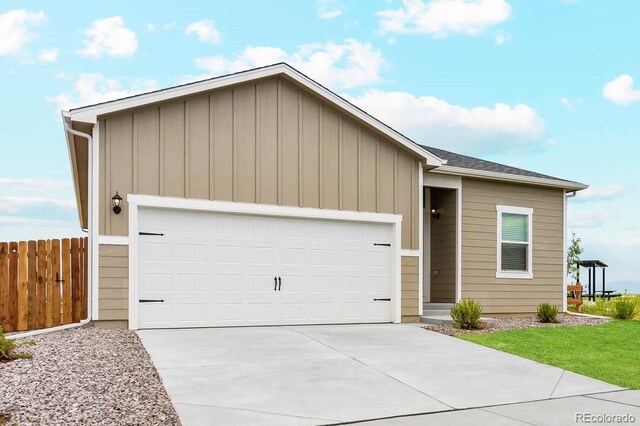 ranch-style house with fence, an attached garage, board and batten siding, and driveway