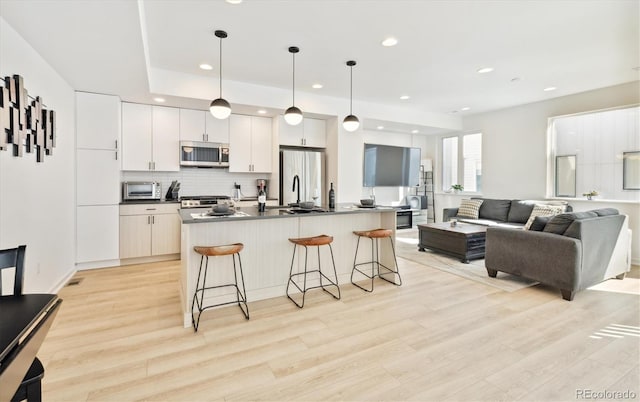 kitchen featuring pendant lighting, a breakfast bar, white cabinetry, and appliances with stainless steel finishes