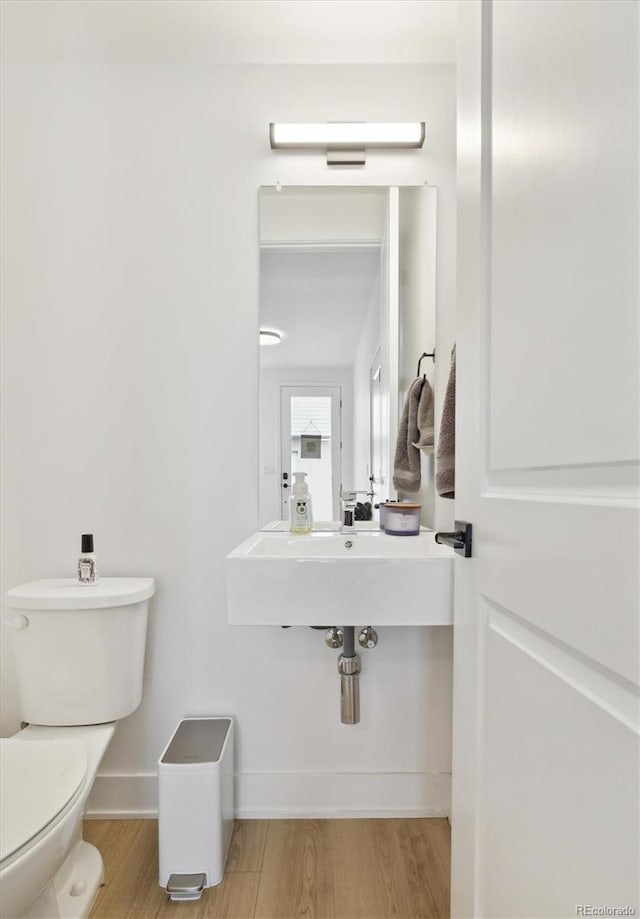 bathroom with toilet and hardwood / wood-style flooring