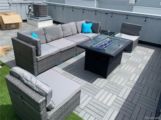 view of patio featuring central air condition unit and an outdoor living space with a fire pit