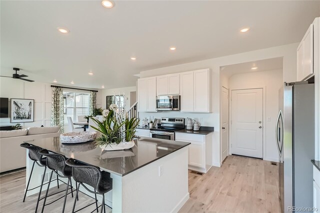 5572 Runge Ct, Timnath, CO 80547 - kitchen featuring white cabinetry, dark countertops, a kitchen island, and stainless steel appliances
