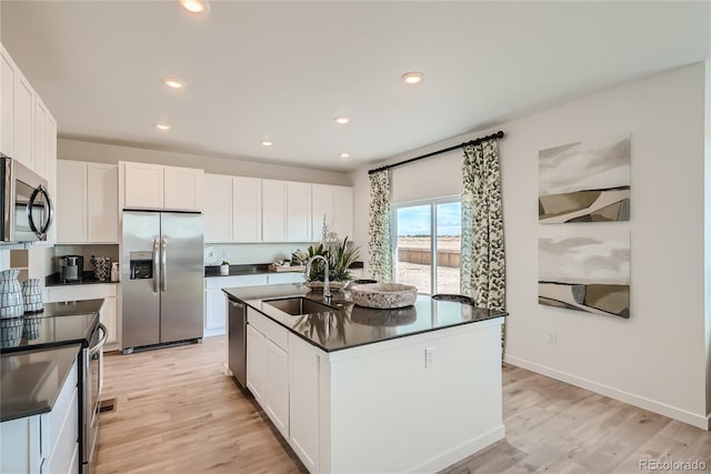 5572 Runge Ct, Timnath, CO 80547 - kitchen with white cabinets, light wood finished floors, dark countertops, appliances with stainless steel finishes, and a sink