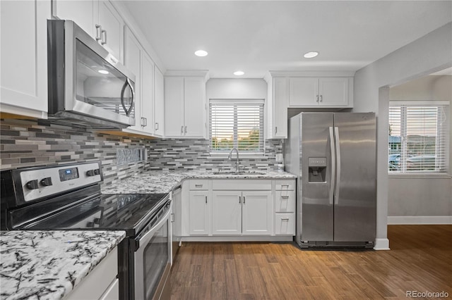 kitchen with dark wood-type flooring, sink, white cabinetry, light stone counters, and stainless steel appliances