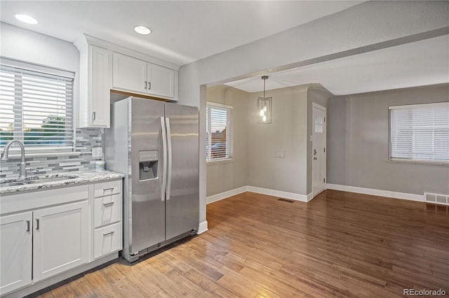 kitchen featuring sink, light stone counters, stainless steel fridge, light hardwood / wood-style floors, and white cabinets