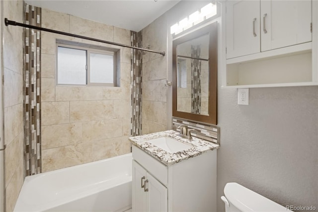 full bathroom featuring tiled shower / bath combo, vanity, and toilet