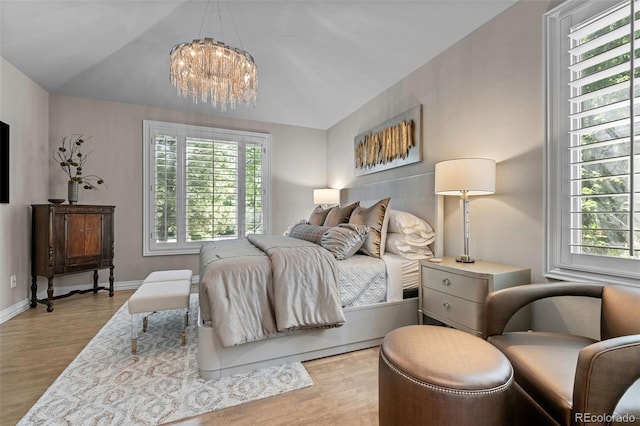 bedroom with vaulted ceiling, light hardwood / wood-style floors, and multiple windows