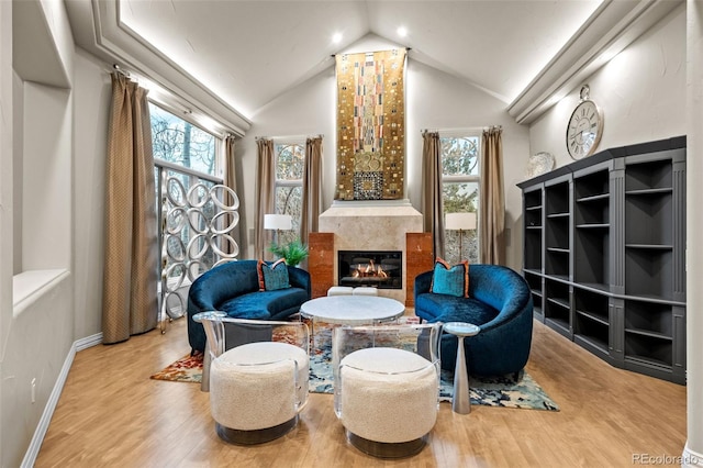 living area with vaulted ceiling, a healthy amount of sunlight, and light hardwood / wood-style floors