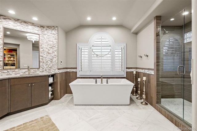 bathroom with vaulted ceiling, separate shower and tub, tile walls, and vanity