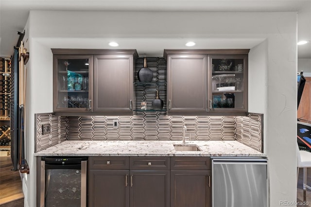 bar featuring sink, log walls, beverage cooler, stainless steel dishwasher, and dark brown cabinets