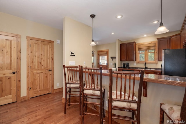 230 Buckhorn Cir, Granby, CO 80446 - kitchen featuring freestanding refrigerator, dark countertops, a sink, light wood finished floors, and a breakfast bar area