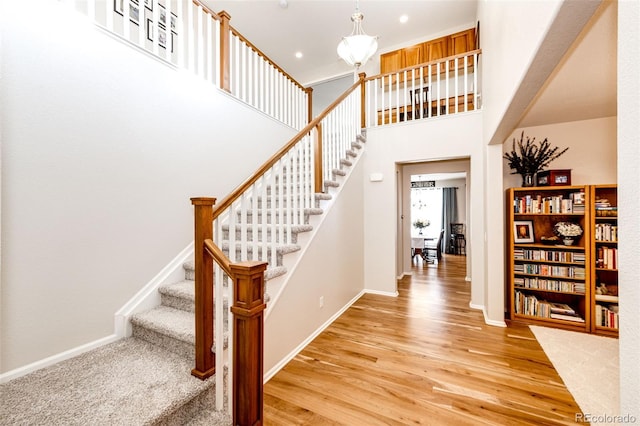 staircase with a high ceiling and hardwood / wood-style floors