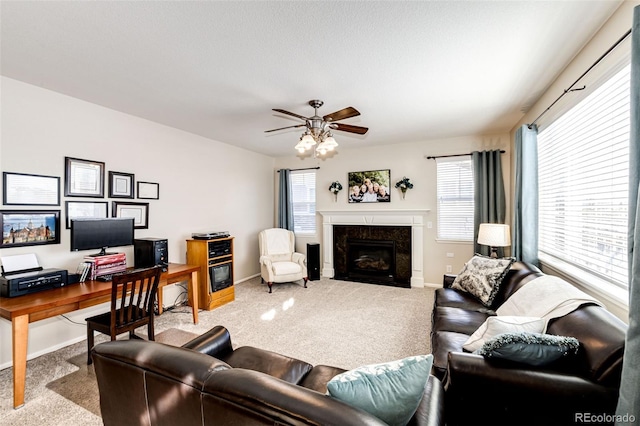 carpeted living room featuring a wealth of natural light, a high end fireplace, and ceiling fan