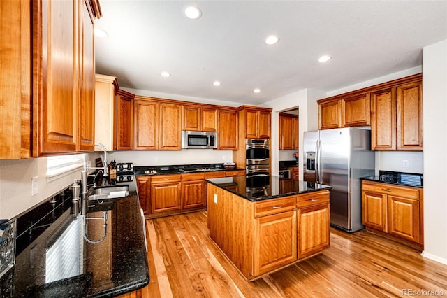 kitchen with appliances with stainless steel finishes, a kitchen island, dark stone counters, and sink