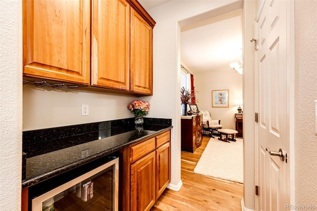 kitchen featuring wine cooler, light wood-type flooring, and dark stone countertops