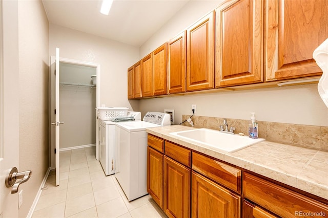 washroom featuring washing machine and dryer, cabinets, light tile patterned floors, and sink