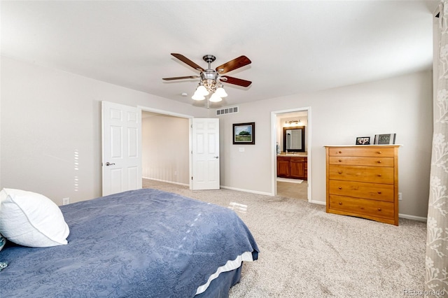 bedroom with ceiling fan, ensuite bathroom, and light carpet