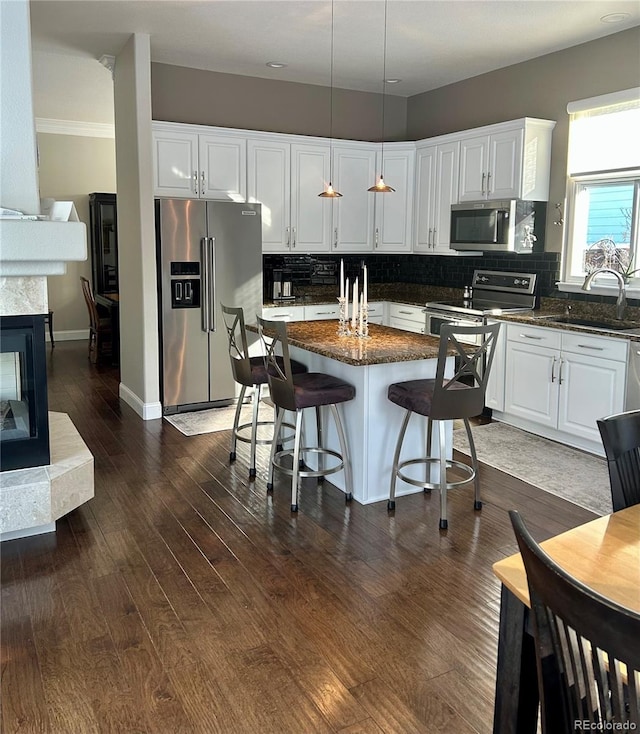 kitchen with white cabinetry, appliances with stainless steel finishes, sink, and a center island