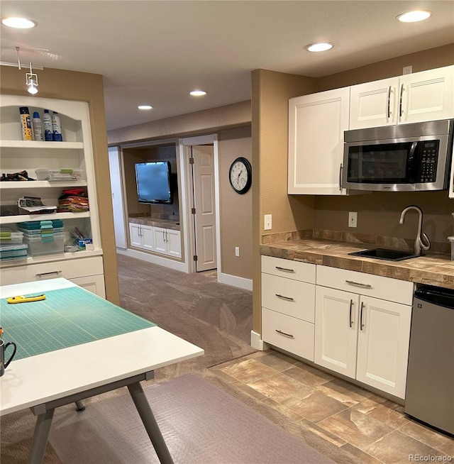 kitchen with white cabinetry, sink, light colored carpet, and appliances with stainless steel finishes