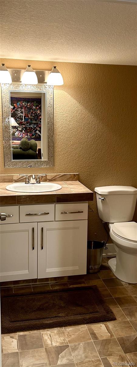 bathroom featuring vanity, a textured ceiling, and toilet