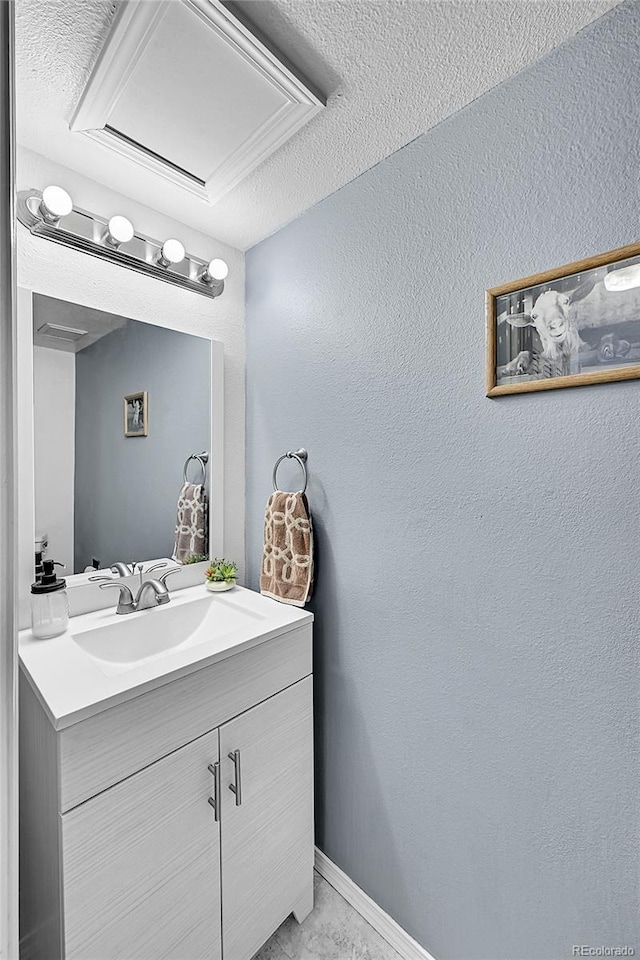 bathroom with a textured wall, vanity, and baseboards