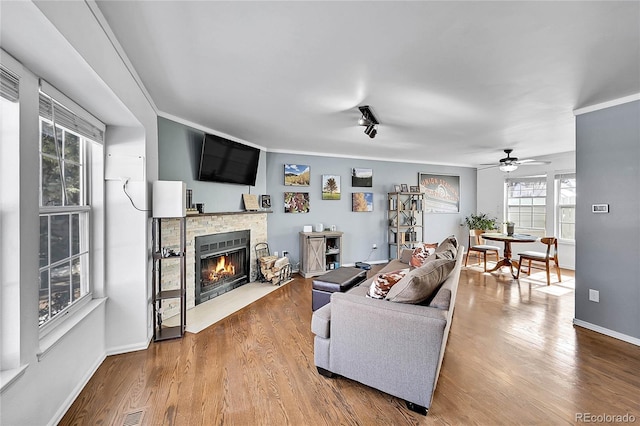 living area featuring visible vents, ornamental molding, wood finished floors, and a stone fireplace