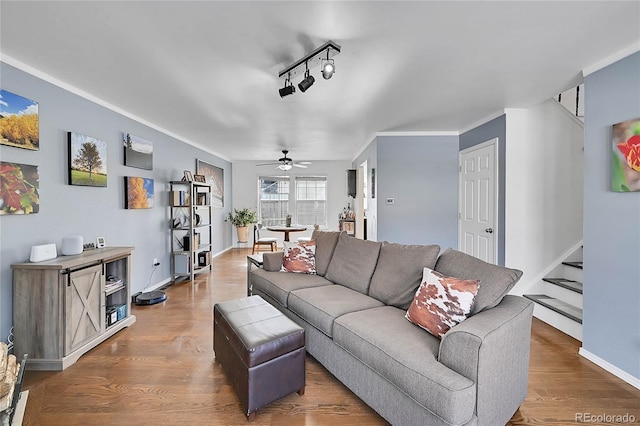 living room featuring stairway, a ceiling fan, track lighting, wood finished floors, and baseboards