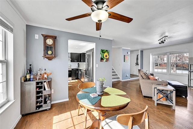 dining area with crown molding, stairway, baseboards, and wood finished floors