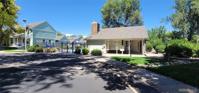 view of front of house with covered porch, a chimney, and fence