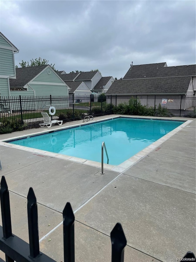 community pool featuring a patio, fence, and a residential view