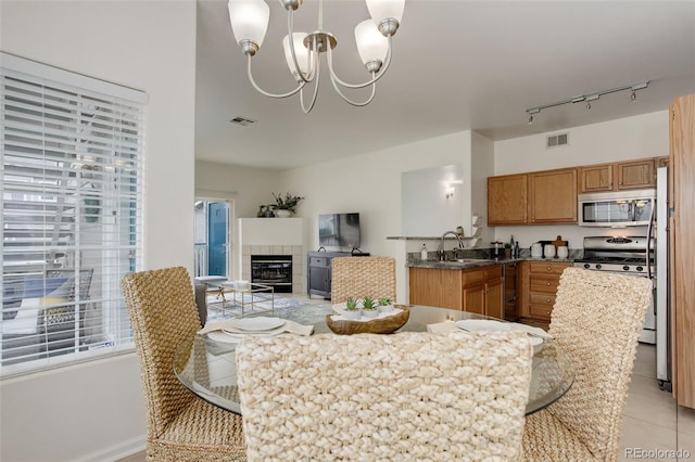 8415 Pebble Creek Way Unit 102, Highlands Ranch, CO 80126 - dining room with a chandelier, light tile patterned floors, track lighting, and a tiled fireplace