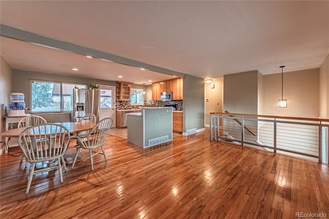 kitchen featuring light wood-style flooring, a center island, backsplash, and appliances with stainless steel finishes