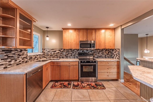kitchen with stainless steel appliances, light countertops, a sink, and decorative backsplash
