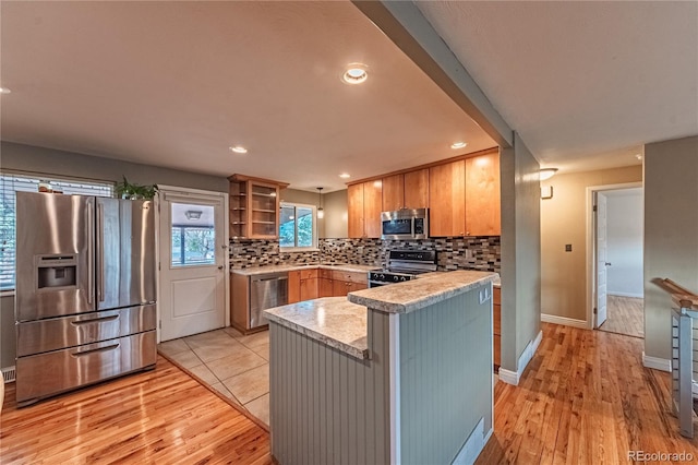 kitchen featuring light countertops, appliances with stainless steel finishes, light wood-style floors, recessed lighting, and decorative backsplash