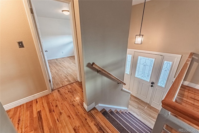 entryway featuring wood finished floors, baseboards, and stairway