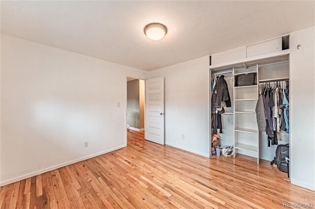 unfurnished bedroom featuring a closet, baseboards, and hardwood / wood-style floors