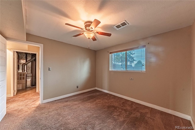 carpeted empty room with visible vents, baseboards, a ceiling fan, and a textured ceiling