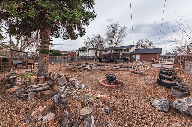 view of yard with a fire pit, a wooden deck, fence, and a vegetable garden