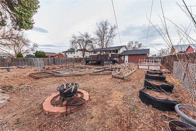view of yard featuring a garden, a fenced backyard, and an outdoor fire pit