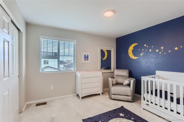 bedroom with a closet, a crib, and light carpet