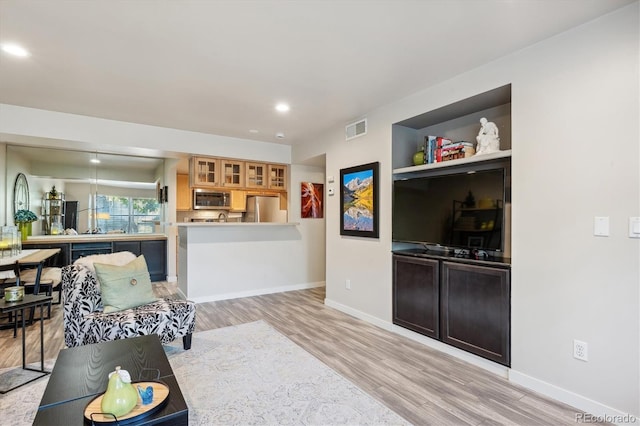 living room featuring built in shelves and light hardwood / wood-style floors