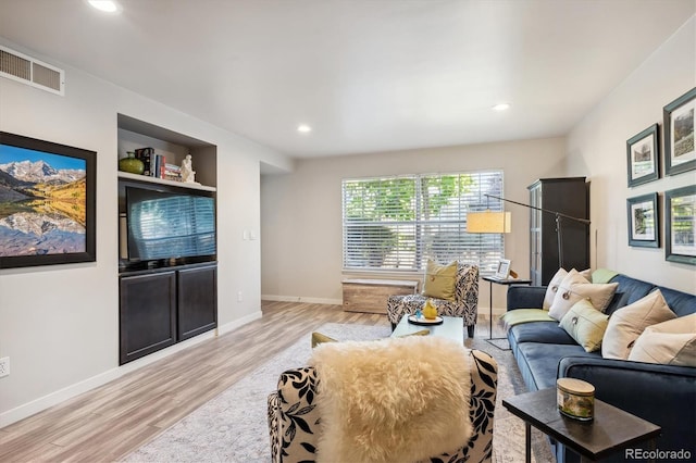 living room featuring built in features and light hardwood / wood-style floors