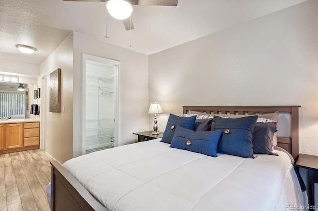 bedroom featuring ensuite bathroom, a spacious closet, light wood-type flooring, a closet, and ceiling fan