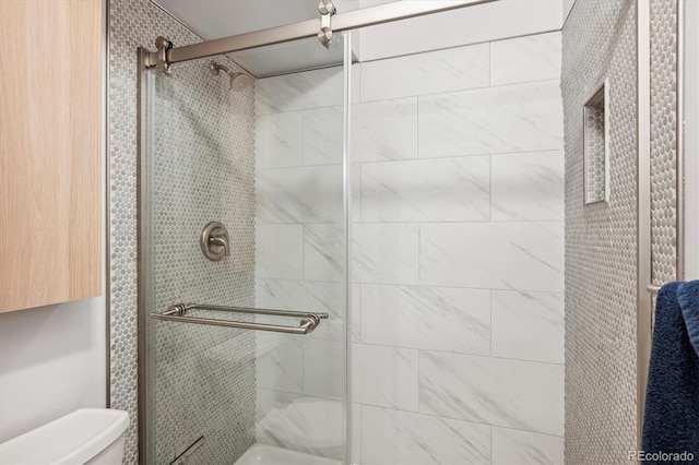 bathroom with a shower with shower door and toilet