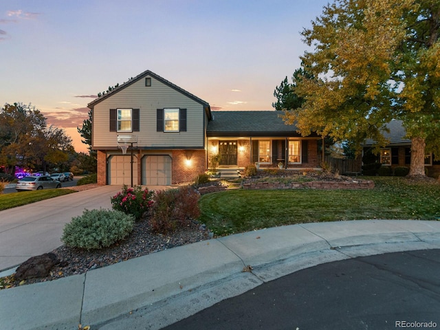 split level home with a garage, brick siding, fence, concrete driveway, and a yard