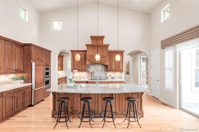 3143 Elmira St, Denver, CO 80238 - kitchen with arched walkways, a towering ceiling, light wood finished floors, tasteful backsplash, and a kitchen breakfast bar